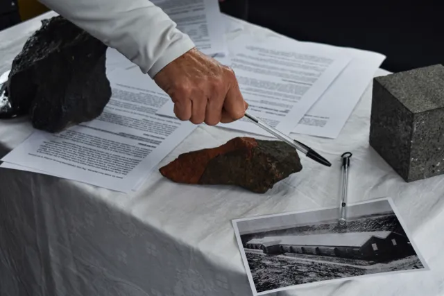 A person pointing a pen towards the artefacts Nicholas Burridge brought in to accompany his artist talk