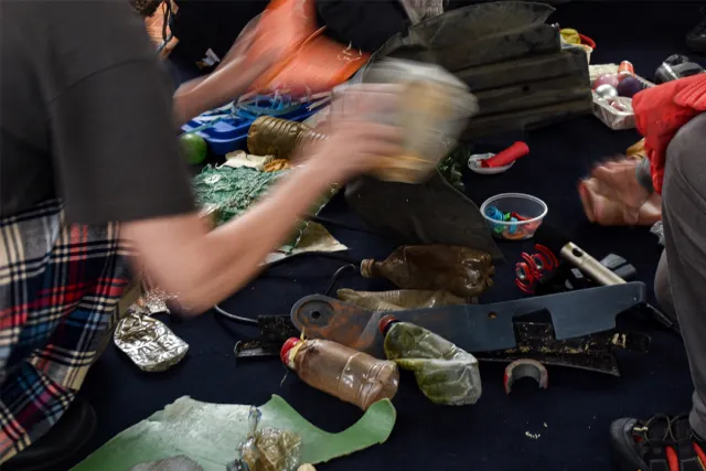 A participant interacting with the collection of plastic pollution Resonant Pollution assembled on the floor of the Tramboat